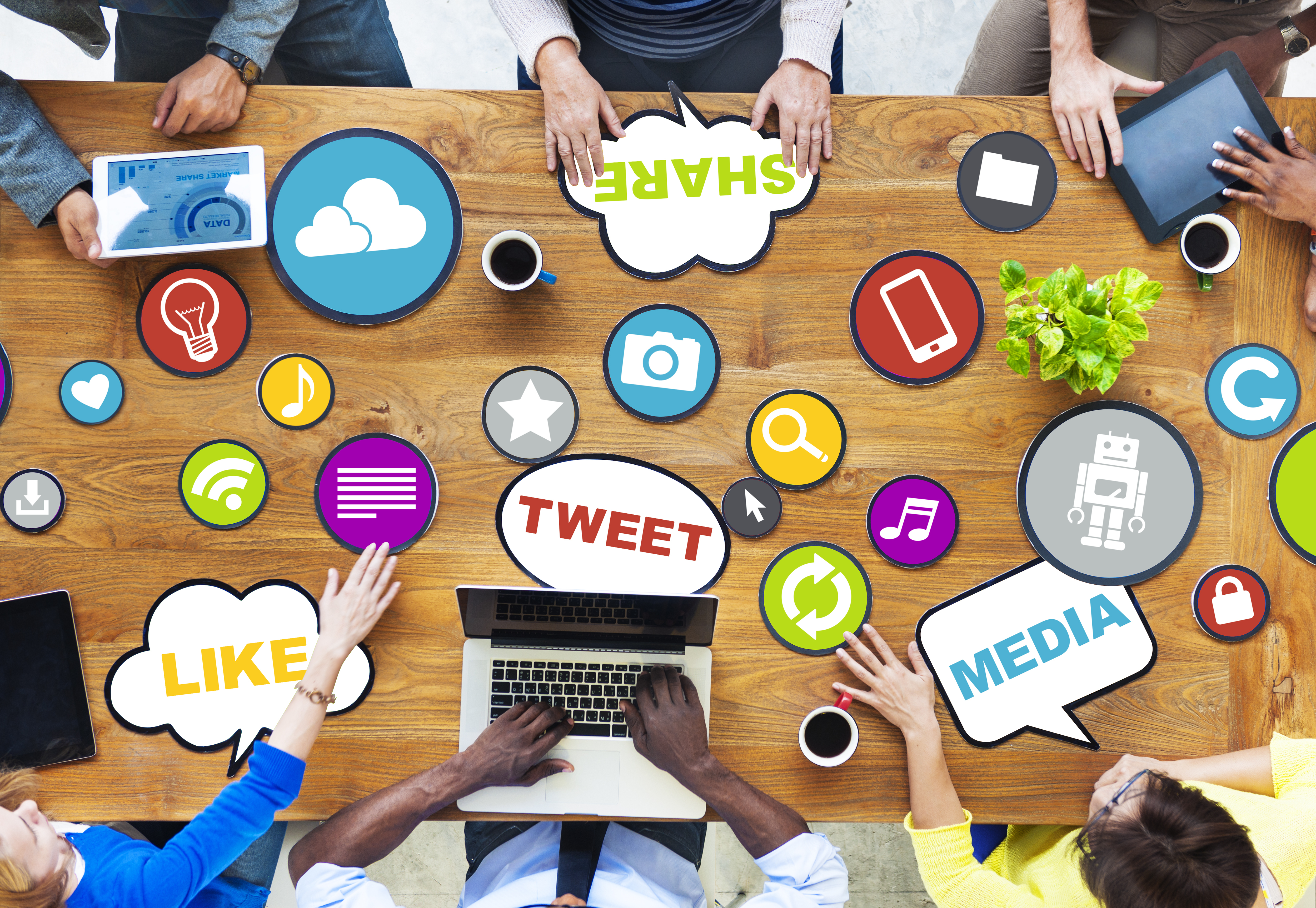 people sitting around a table talking and using electronic devices